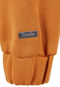 Tissu orange texturé avec un design à côtes et des poignets élastiques. Présente une étiquette en argent avec la marque "Dropside".