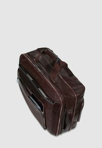 Braune Lederhandtasche mit mehreren Fächern, Reißverschlüssen und einem robusten oberen Griff. Akzente setzen blaue Nähte und ein schlankes Design.