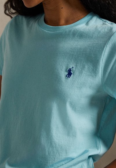 Φωτεινό γαλάζιο βαμβακερό μπλουζάκι με στρογγυλή λαιμόκοψη και κοντά μανίκια. Διαθέτει ένα μικρό σκούρο μπλε κεντημένο λογότυπο στο στήθος.