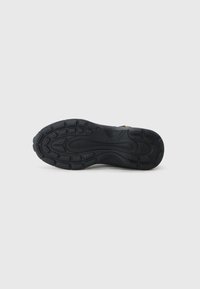 Suela de zapato deportivo negra con una superficie texturizada, que presenta patrones de relieve para agarre y soporte, fabricada con material de goma duradero.