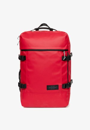 Červený batoh s hladkým, lesklým povrchem. Obsahuje černé popruhy, klipsy a nášivku s logem. Čtvercový tvar s horním uchycením a zipovým uzávěrem.