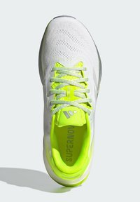 Weißer Sportschuh mit strukturiertem Obermaterial, neongelben Schnürsenkeln und passender Einlegesohle. Verfügt über reflektierende Akzente und eine gepolsterte Sohle.