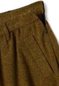 Pantalon moutarde à motif chevrons avec une fermeture éclair latérale et un design plissé, réalisé dans un tissu texturé avec une teinte chaude et douce.