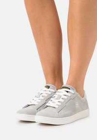 Gray suede sneakers with white laces and a white rubber sole. Features a logo on the side and a padded collar for comfort.