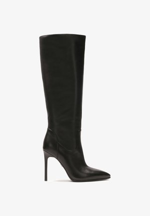 Botte noire en cuir au-dessus du genou avec un bout pointu et un talon aiguille haut. Dispose d'une texture lisse et d'une silhouette élégante.