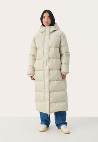 Gevoerde lange jas in lichtbeige, met een hoge kraag, capuchon en zijzakken. De soepele textuur en het gestikte ontwerp zorgen voor een comfortabele pasvorm.
