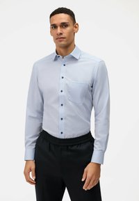 Himmelblaues Langarmhemd in Slim-Fit, mit einer Brusttasche und kontrastierenden dunklen Knöpfen. Kombiniert mit schwarzen Hose mit elastischem Bund.