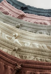 Bermudas de cintura elástica en cuatro colores: verde oscuro, rosa, verde claro y beige. Cada una cuenta con un cordón ajustable y una tela texturizada.