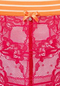 Rote Spitzenunterwäsche mit filigranen floralem Muster, einem gestreiften orangenen Bund und einem kleinen orangenen Schleifendetail mit einer Glockenakzent.
