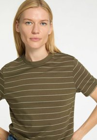 T-shirt verde oliva con strisce orizzontali bianche, maniche corte e scollatura rotonda, realizzato in un tessuto morbido e elasticizzato.