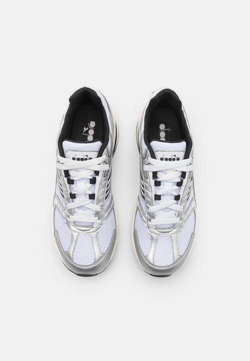 Scarpe sportive bianche con dettagli argentati, parte superiore in rete e bordo nero. Presentano lacci bianchi e un colletto imbottito per il comfort.