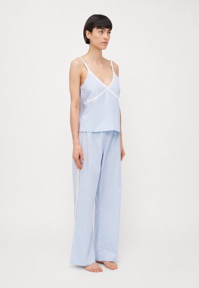 Light blue sleepwear set featuring a tank top with lace trim and loose-fit pants with side detailing. Made from soft, lightweight fabric.