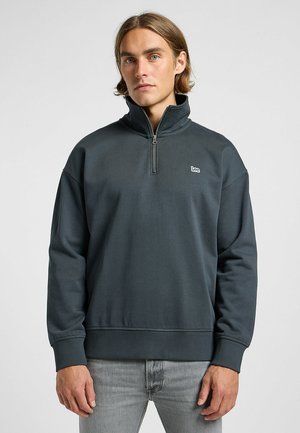 Mørkegrå kvart-zip sweatshirt med høj krave, ribbede håndled og logo på brystet. Blødt, tekstureret stof, afslappet pasform.