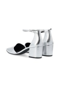Chaussures à talons hauts argentées avec une finition texturée, côtés ouverts et brides de cheville. Design de talon bloc avec une apparence lisse et polie.