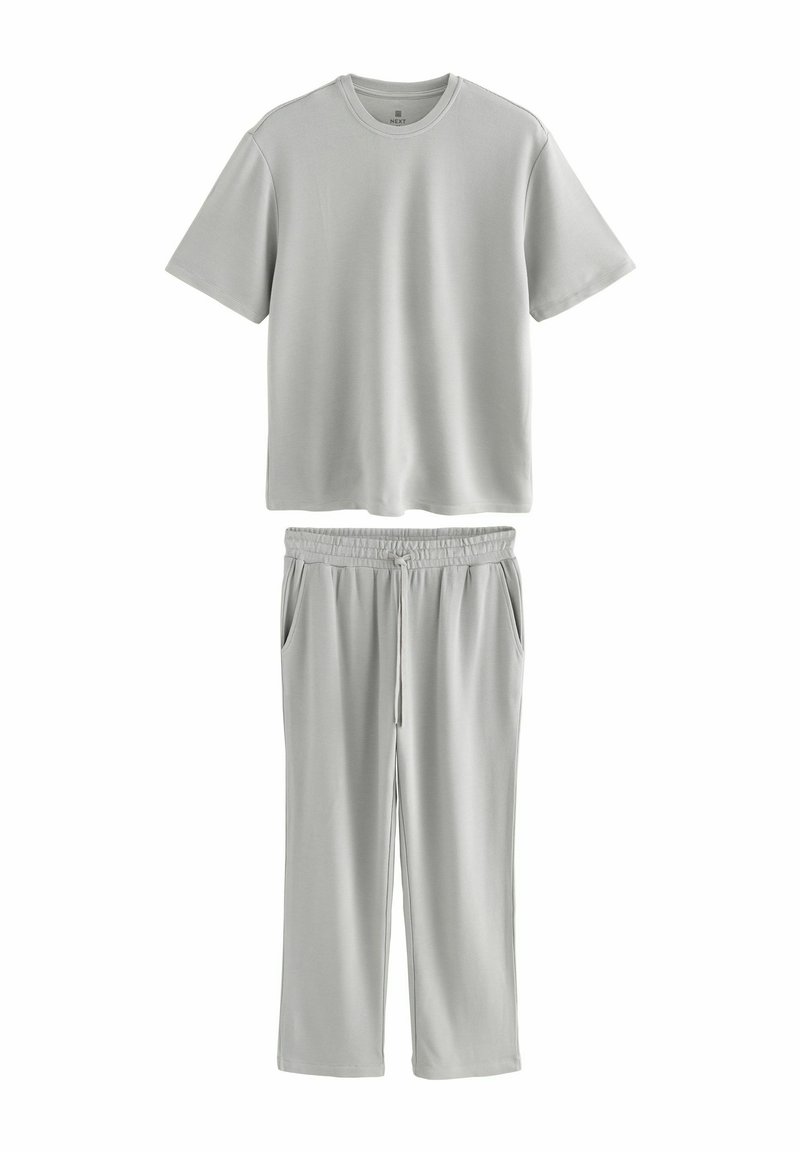 Lys grå, T-shirt med kort ærme og rund hals, der er parret med matchende, sweatpants med elastisk talje, side lommer og en afslappet pasform.