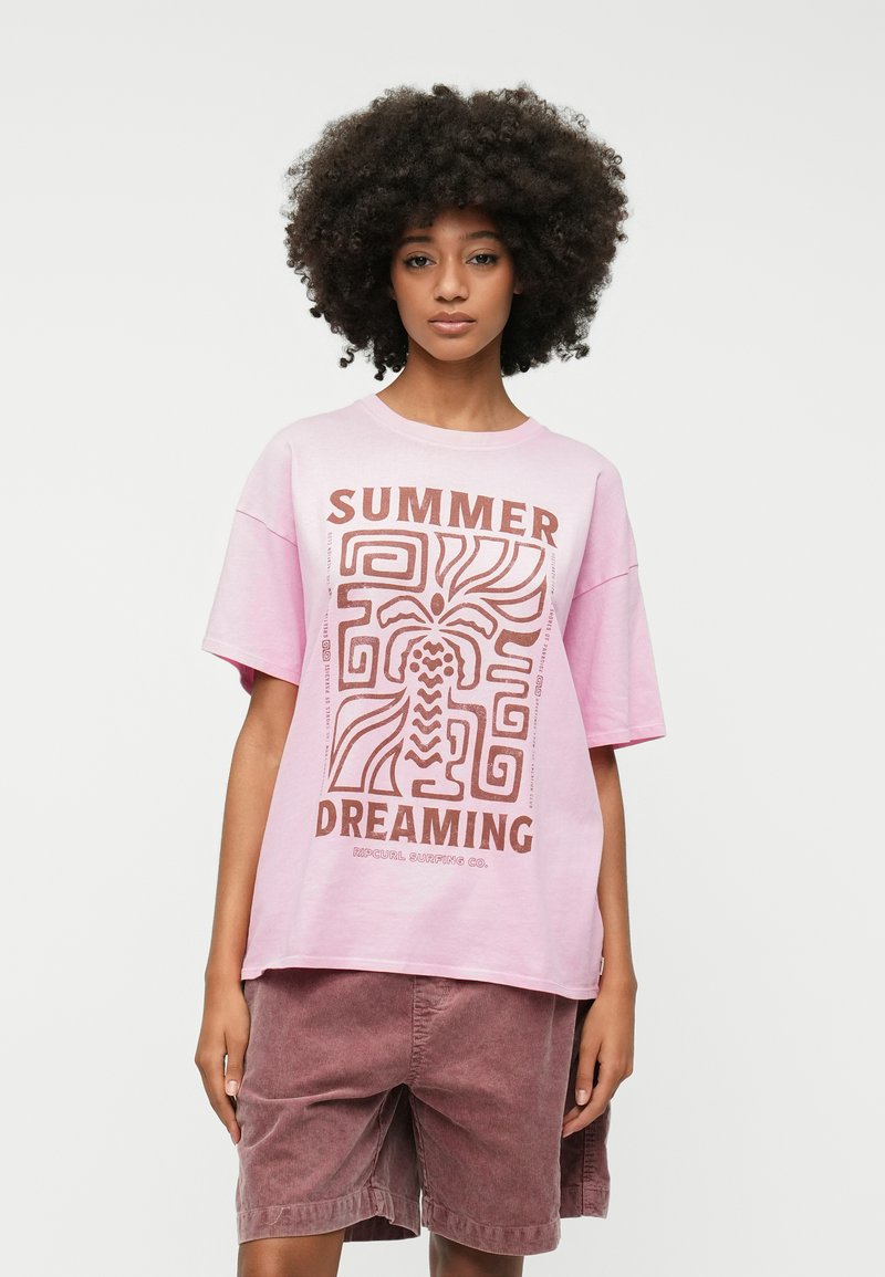 Pink oversized t-shirt featuring "SUMMER DREAMING" graphic in brown, with abstract plant and geometric designs. Worn with brown corduroy shorts.