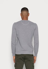 Pull gris en tricot avec manches longues et col rond. Présente un motif texturé et des bordures côtelées autour du col, des poignets et de l'ourlet.