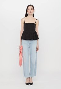 Black peplum top made of textured fabric, paired with light blue wide-leg jeans. Accessories include a pink satin bag and black pointed-toe heels.