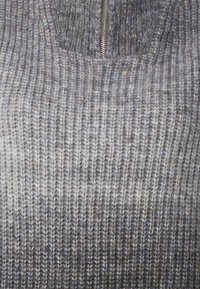 Strickpullover in gedämpften Grautönen, mit einem Reißverschluss am Hals und einem gerippten Textur mit variierenden Streifenmustern.