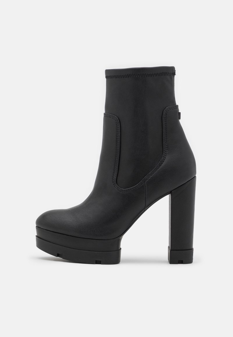 Bottine noire à talon haut avec une semelle plateforme épaisse et une finition en cuir lisse, vue de profil sur un fond uni.
