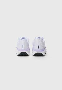 Bakfas av hvite og lavendel sneakers med mesh overdel, polstret krage og kontrasterende svart såle, med en teksturert overflate.