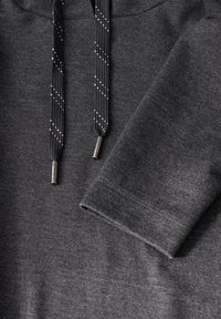 Donkergrijze hoodie met een gestructureerde stof, een trekkoord met zwarte en zilveren accenten, en een opgerolde mouwdetail.