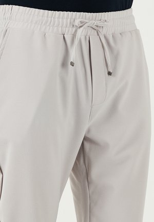 Pantaloni jogger grigio chiaro realizzati in tessuto testurizzato, con vita elastica, chiusura con laccetto e dettagli con tasche laterali.