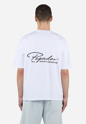 Weißes Baumwoll-T-Shirt mit einem schwarzen, geschwungenen Logo im oberen Rückenbereich, kurzen Ärmeln und einem lockeren Schnitt. Der Text lautet "Pegador Alle Rechte vorbehalten."