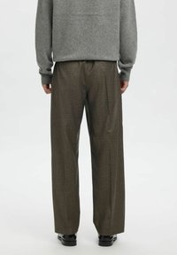 Hall hall, pruunid ruudulise mustriga püksid, lõdva istuvusega, kohandatud disain, volditud ees, lai sääreosa, sile tekstuur, kantud mustade kingadega.