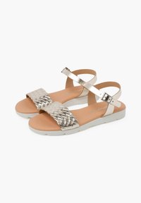 Sandalias con tiras trenzadas doradas y una suela blanca, que cuentan con una correa ajustable en el tobillo y una plantilla acolchada para mayor comodidad.