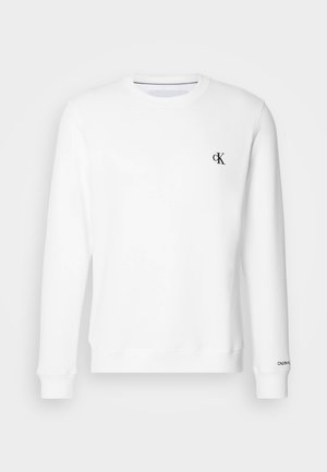 Valge ümmarguse kaelusega sviiter, mis on valmistatud pehmest kangast, kus vasakul rinnal on väike must "CK" logo ning soonikkuulised varrukad ja alläär.
