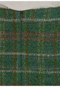 Villahame, jossa vihreä, sininen ja ruskea ruutukuvio, näkyvillä oleva vetoketjusuljin ja teksturoitu kangas.