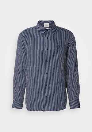 Navy blue button-up shirt with white vertical stripes, long sleeves, pointed collar, and embroidered logo on the chest.