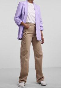 Lila kavaj, vit t-shirt och beige högmidjade vida byxor. Sneakers med gråton kompletterar outfiten. Enkelt design, avslappnad passform.