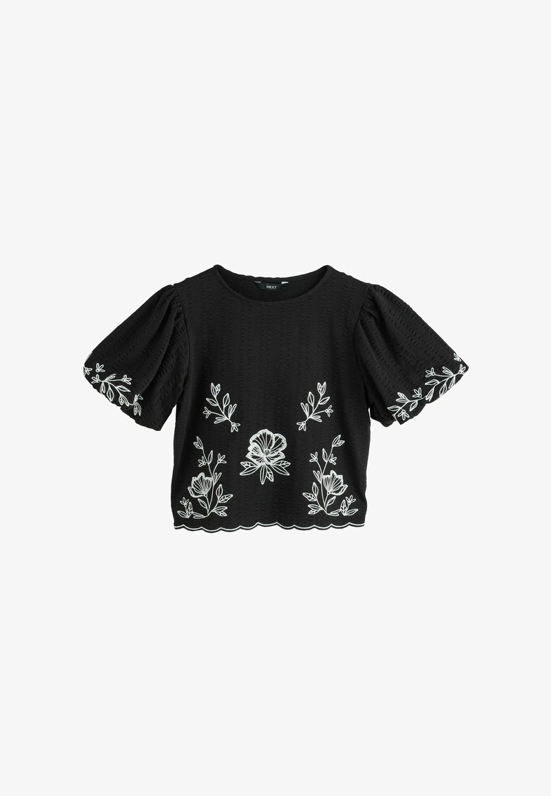 Černá halenka s krátkými rukávy a nabíranými rukávy, s bílou květinovou výšivkou na přední straně, rukávech a vlnitém okraji.