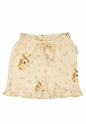 Vaalean beige lyhyet shortsit, joissa on sifonkihelma ja toistuva kuvio sarjakuvahahmoista ja kukista, valmistettu pehmeästä ja kevyestä kankaasta.