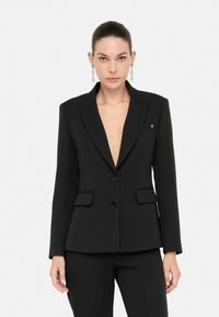 Černý blazer s hlubokým výstřihem do V, jedním knoflíkem a dvěma předními kapsami. Hladká textura a přiléhavý střih. Malá loga na klopě.