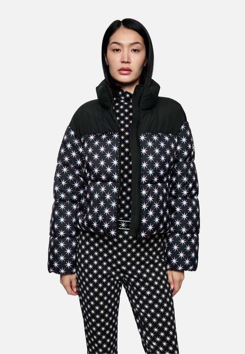Daunenjacke mit einem schwarzen oberen Abschnitt und einem Sternmuster in Weiß und Blau, mit einem Reißverschluss vorne und hohem Kragen, kombiniert mit passenden Hosen.