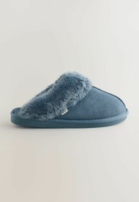 Blå ruskinds-tøffel med blødt, kunstpelsfor. Rund form, flad sål og syede detaljer. Synlig mærkebelægning.