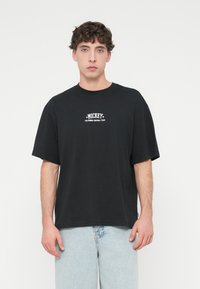 Μαύρο βαμβακερό μπλουζάκι με κοντά μανίκια, με λευκή επιγραφή "MICKEY CALIFORNIA FOOTBALL TEAM" και αστέρια, σχεδιασμένο για άνετη εφαρμογή.