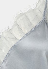 Ljusblå satinfabric med genomskinlig volangkant längs kanten. Slät textur med detaljerad sömnad.