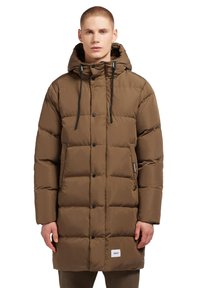 Bruine pufferjas met capuchon, voorzien van een knoopsluiting, zwarte toggles en een logo patch onderaan. Zachte, gewatteerde textuur.