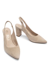 Beige suede slingback heels with a pointed toe and mid-height block heel, featuring a smooth interior and a logo on the insole.