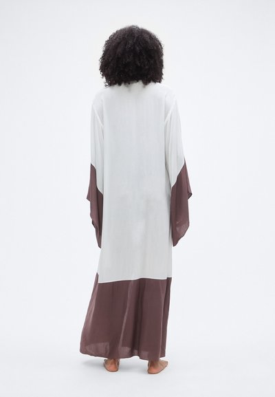 Μακρύ, ελαφρύ μπουρνούζι σε στυλ κιμονό, με λευκό σώμα και καφέ λεπτομέρειες στα μανίκια και το τελείωμα. Μαλακό, ελαστικό ύφασμα με άνετη εφαρμογή.
