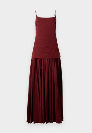 Sleeveless maroon dress with a fitted top and flowing, pleated skirt. Made of lightweight fabric, features thin spaghetti straps.