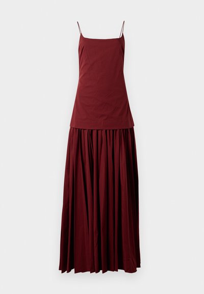 Sleeveless maroon dress with a fitted top and flowing, pleated skirt. Made of lightweight fabric, features thin spaghetti straps.