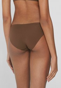 Brąskie, bezszwowe majtki o wysokim kroju, gładkiej fakturze i minimalnych detalach szwów, widok z tyłu.