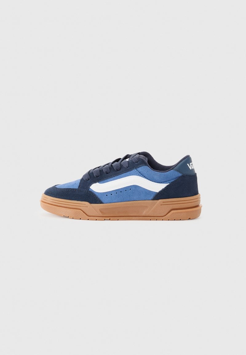 Blue suede sneaker featuring a white side stripe, gum rubber sole, and contrasting dark blue accents. Flat laces complement the design.