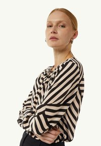 Schwarz-cream-farbene gestreifte Bluse mit Rundhalsausschnitt und langen Ärmeln, aus leichtem Stoff mit einer leicht strukturierten Oberfläche.