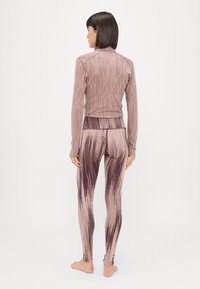 Top ajustado de manga longa e leggings combinando em mauve suave com um padrão linear texturizado. O tecido parece elástico e suave.